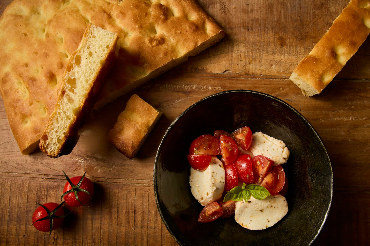 Focaccia mit Tomaten und Burrata auf einem mediterranen Tisch